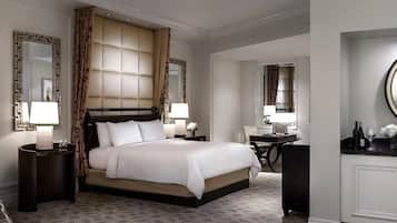 Habitación de hotel con una cama grande, dos mesitas de noche con lámparas, un escritorio con silla y un espejo grande en la pared.