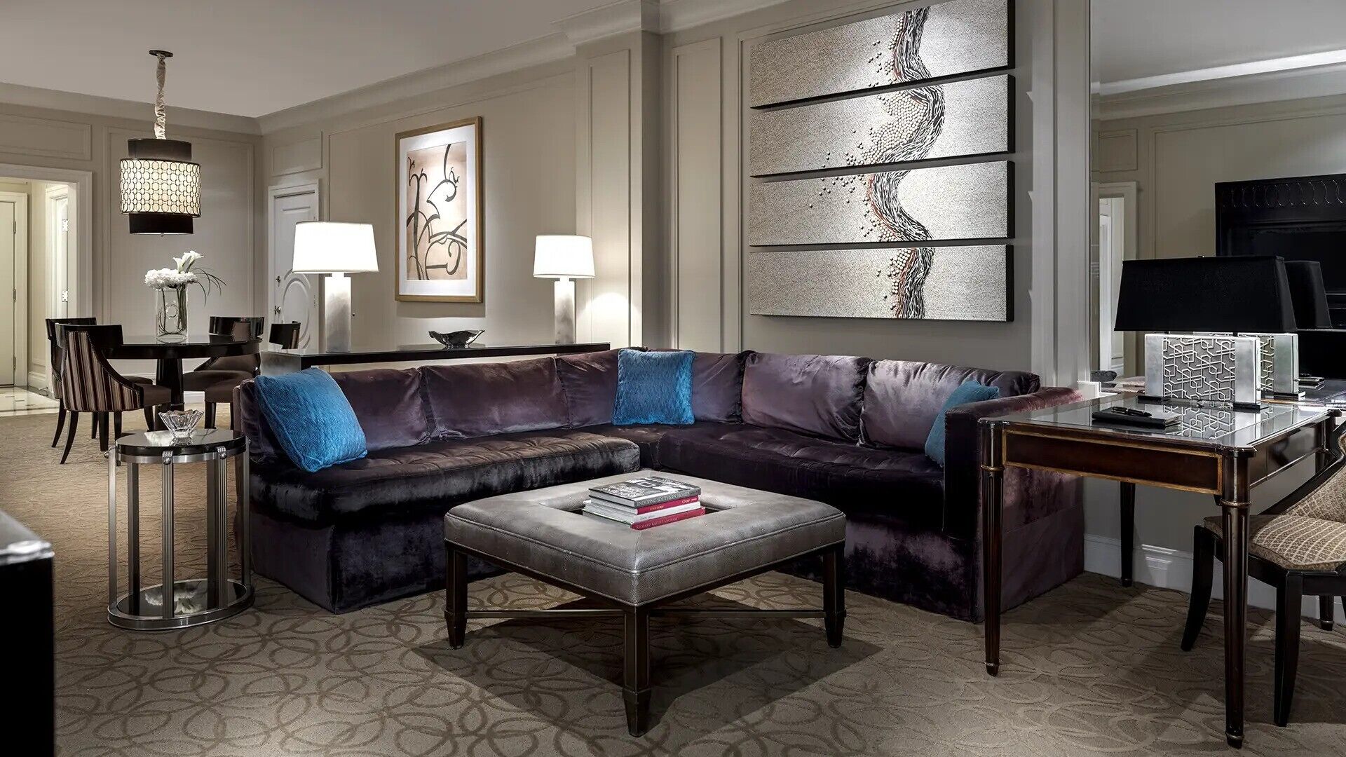 A modern living room with a leather sofa, a coffee table, and a dining area with a chandelier.