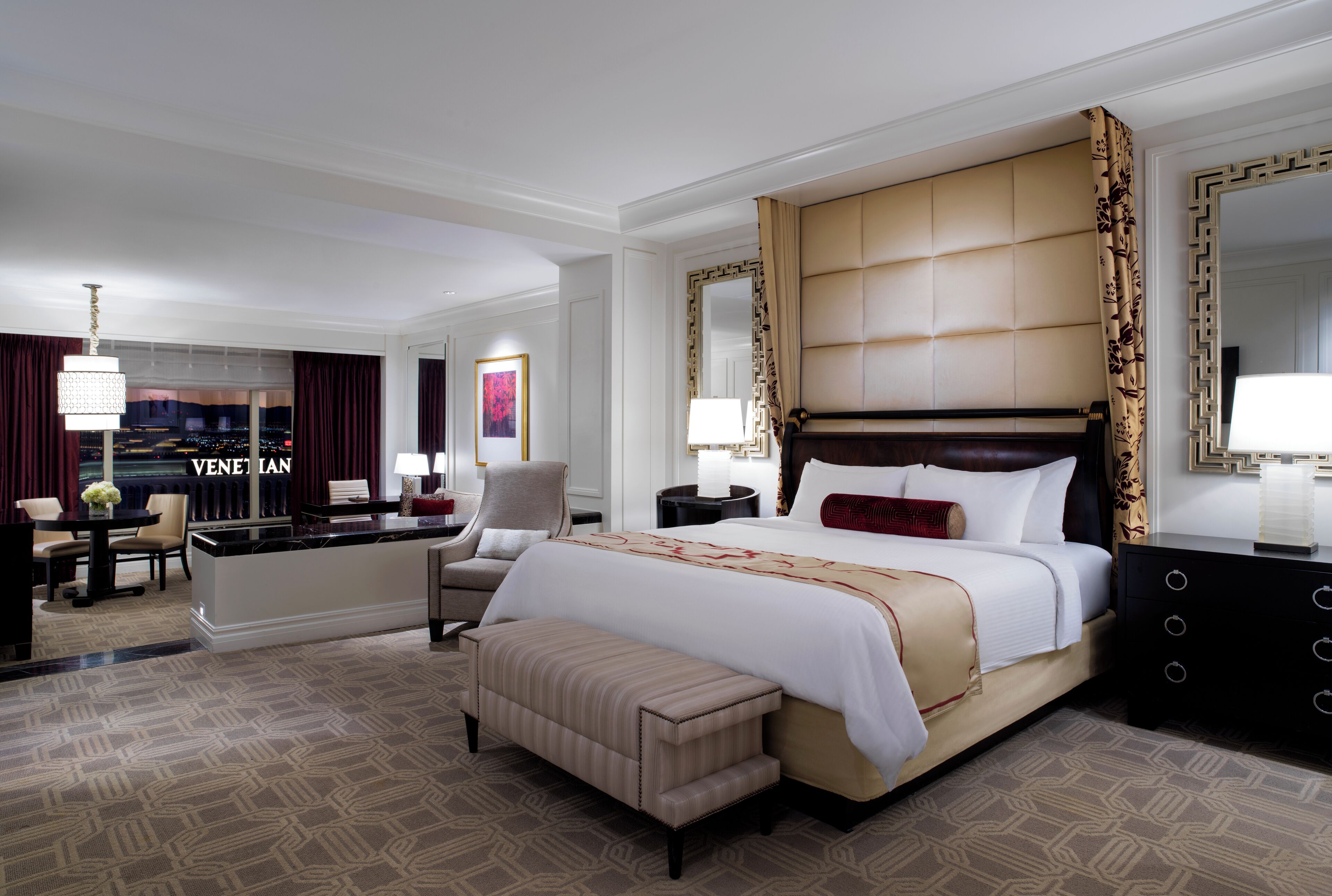 Ein Hotelzimmer mit einem großen Bett, einem Schreibtisch, einem Sessel, einer Bank und einer Minibar.