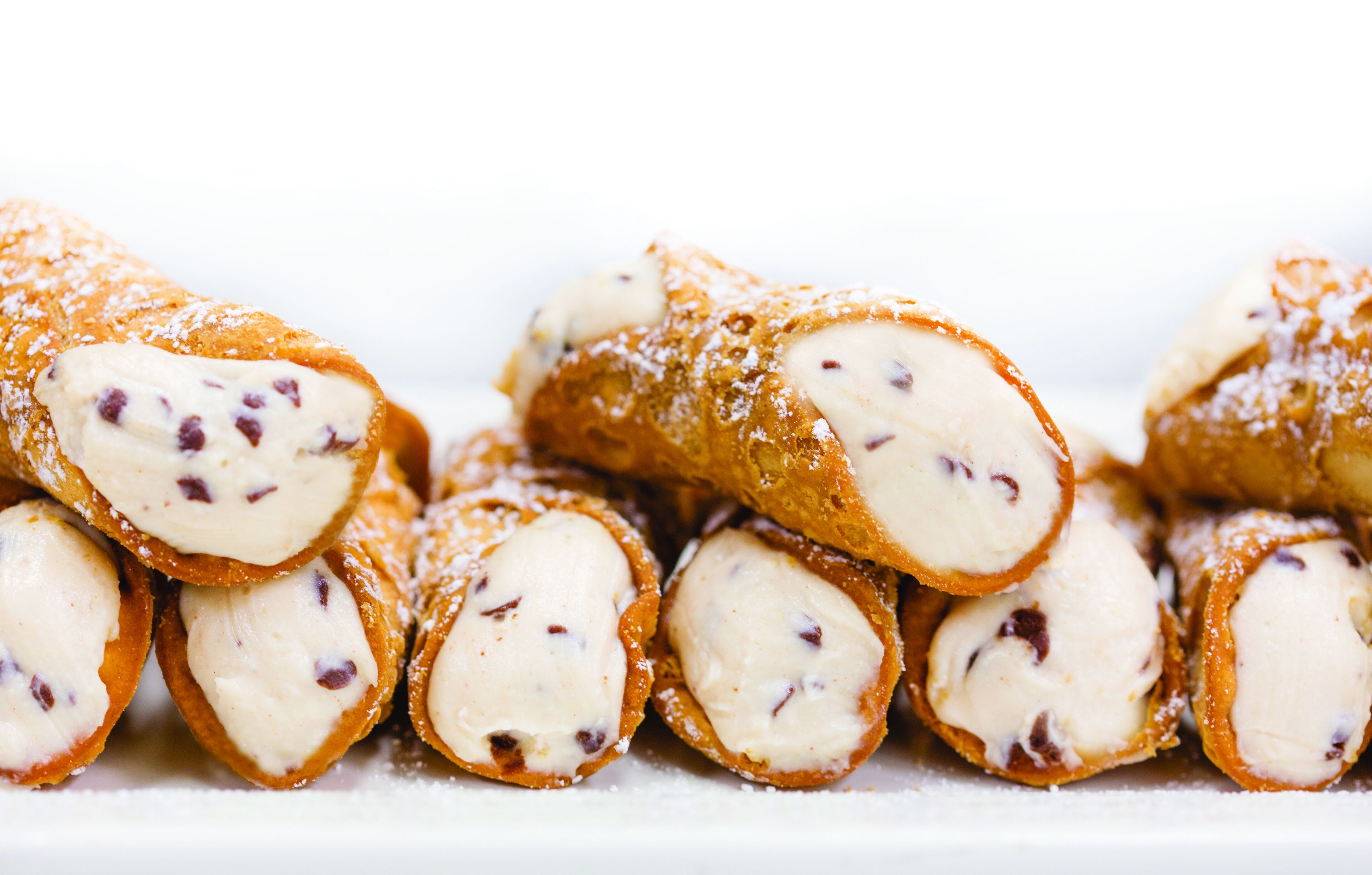 A stack of cannoli with chocolate chips and powdered sugar.