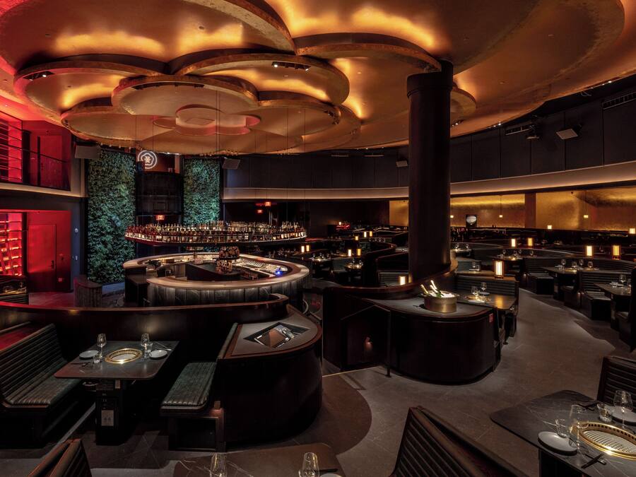 A modern bar area with a circular bar, seating, and a green wall.
