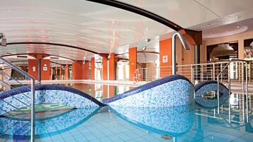 An indoor swimming pool with a tiled floor and a curved glass ceiling.