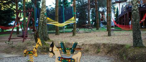 Un parque infantil con columpios, una hamaca y un juego con forma de jirafa.