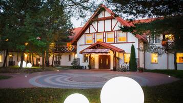 A traditional European-style building with a symmetrical facade, a central entrance with a covered porch, and a circular driveway.