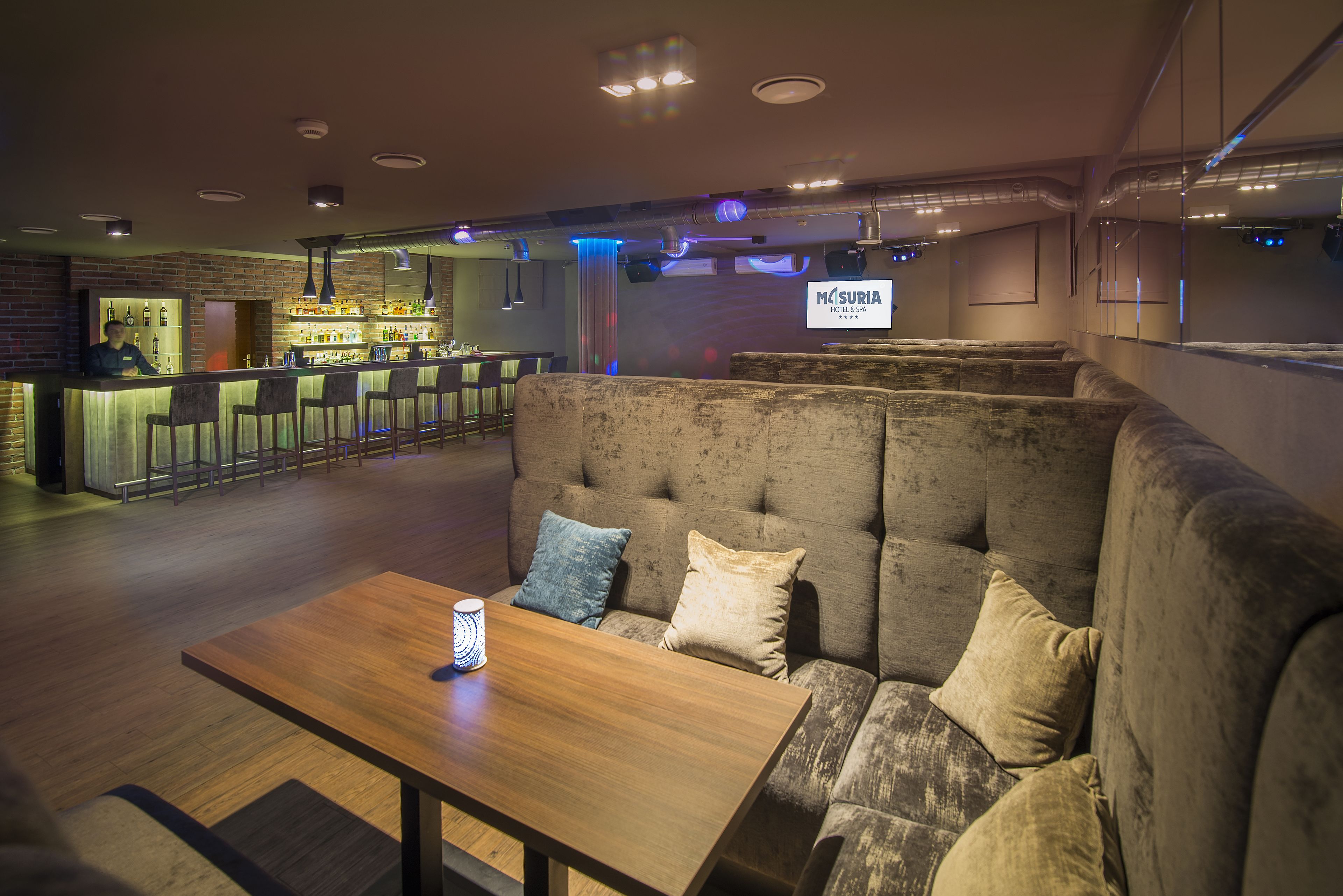A bar area with a bar counter, stools, and a seating area with a sofa and a table.