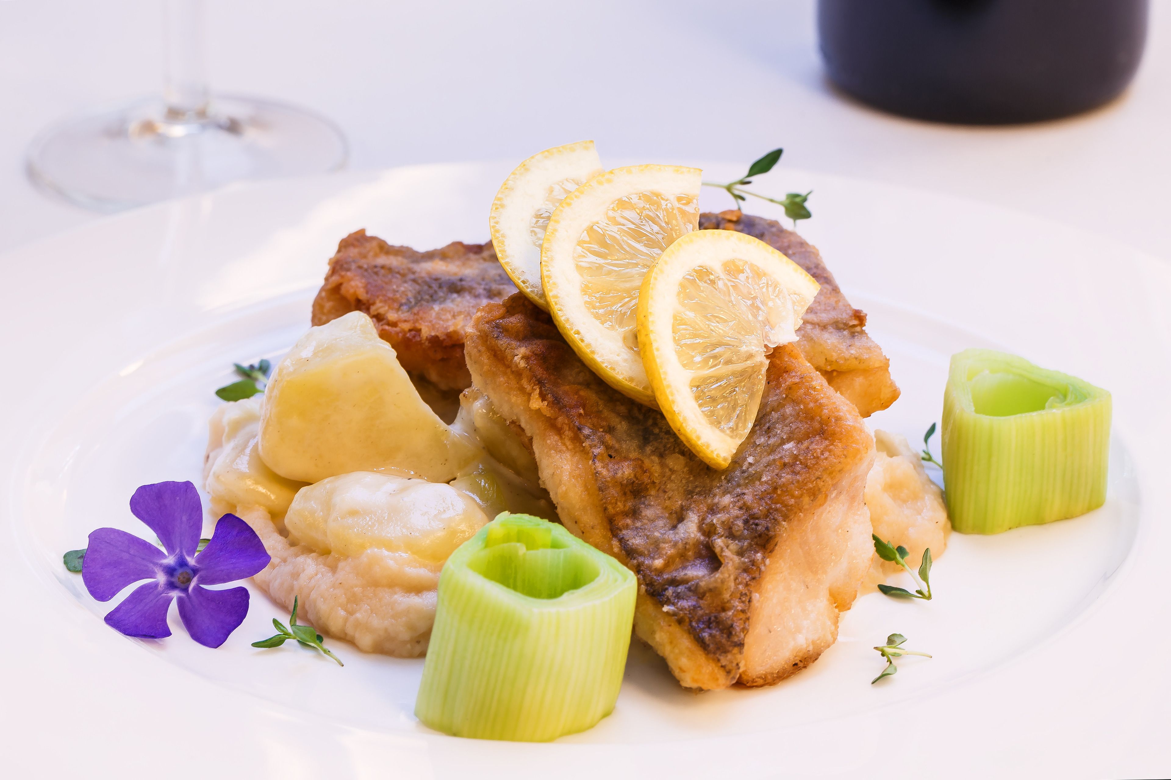 A plate with a piece of meat, lemon slices, and celery.