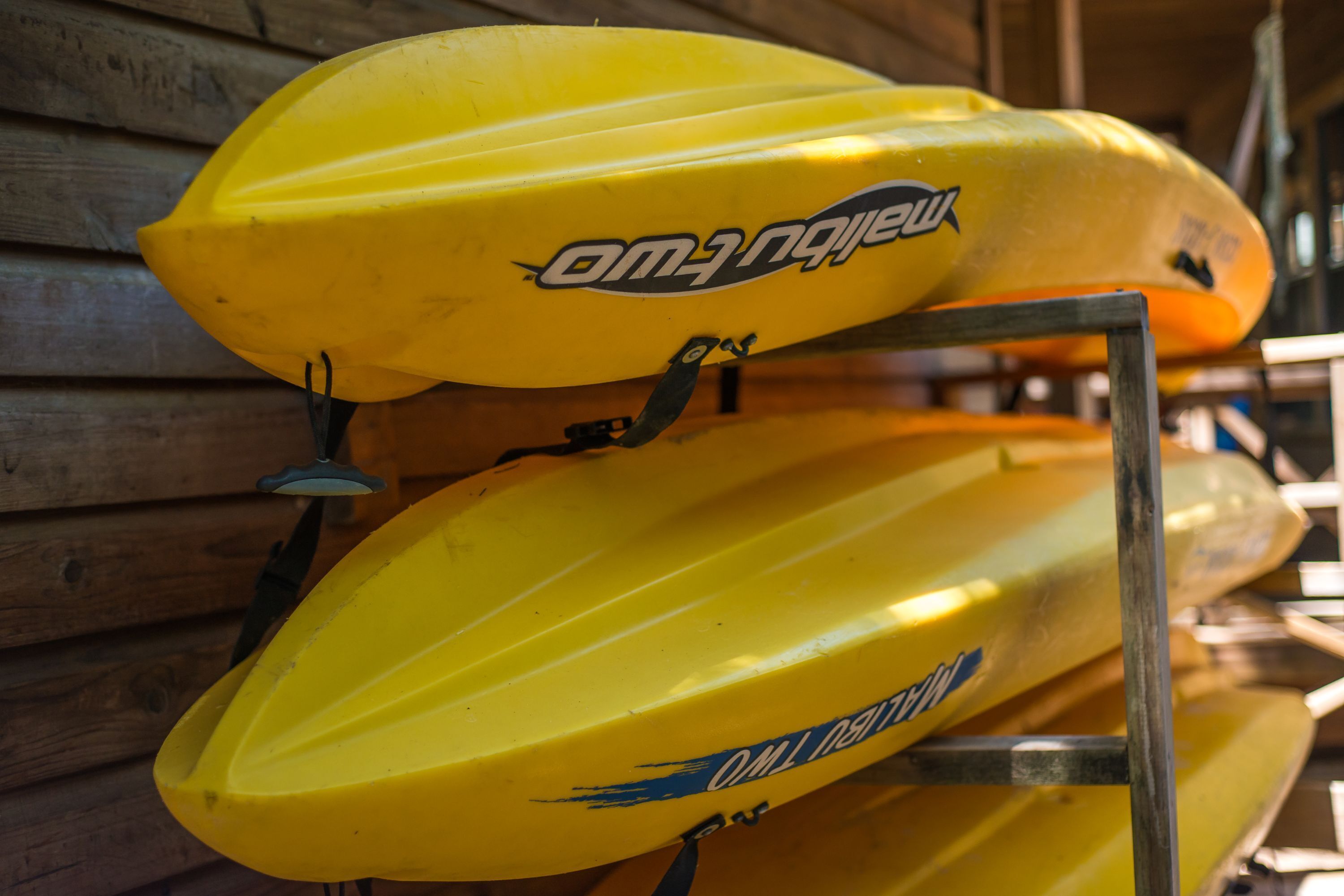 Una hilera de kayaks amarillos con el nombre de marca "OMANO" en un estante metálico.