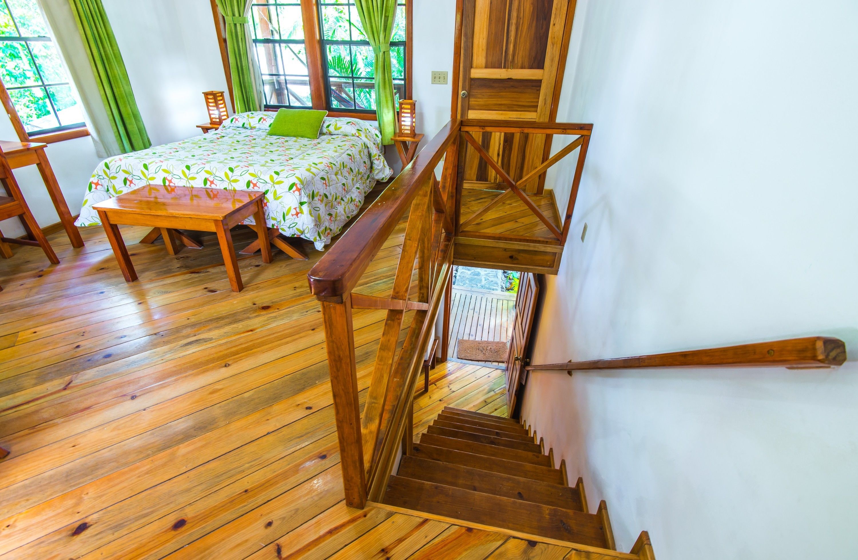 Eine Holztreppe führt zu einem Schlafzimmer mit einem Bett, einem Sessel und einem Tisch.