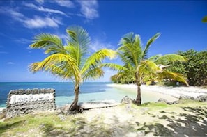 Na praia, areia branca, espreguiçadeiras, guarda-sóis 
