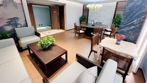A modern living room with a sofa, a coffee table, a dining table, and chairs. There is a painting on the wall and a view of the outdoors. - Golden Ocean Hotel (Tianjin)