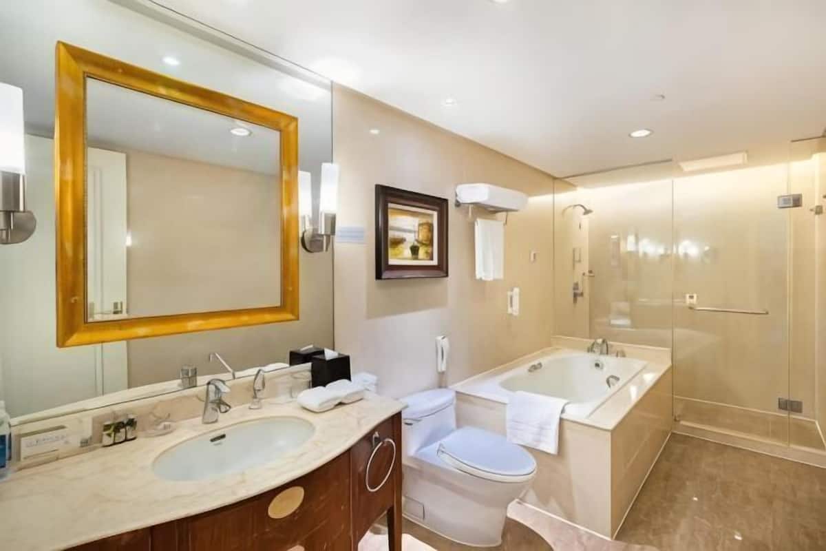 Een hotelbadkamer met een grote spiegel, een bad, een toilet en een douche.