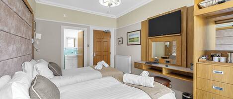 A hotel room with two beds, a TV, a wooden dresser, and a bathroom visible through an open door.