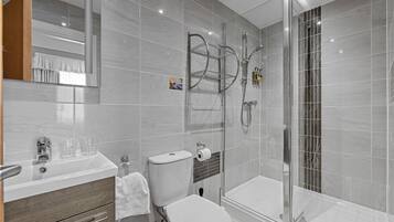 A modern bathroom with a glass shower enclosure, a white toilet, and a vanity with a mirror.