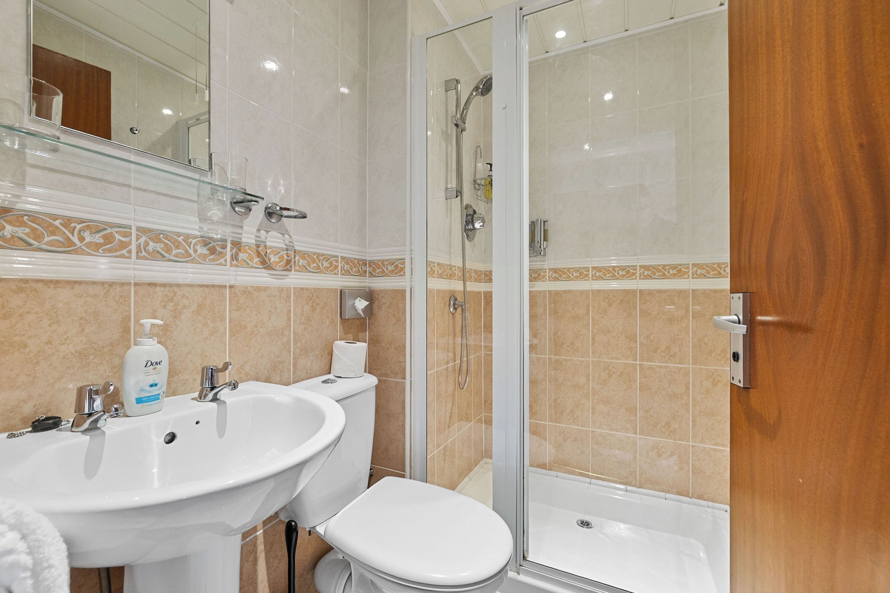 A bathroom with a white sink, toilet, and glass-enclosed shower.