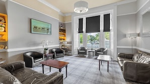 A spacious living room with leather sofas, a wooden coffee table, and a large window with black curtains. - Invicta Hotel (Plymouth)