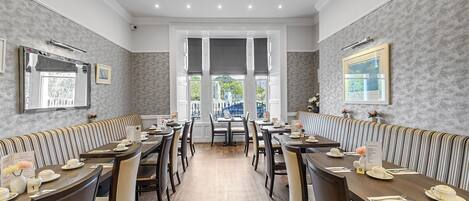 A restaurant with a long counter, booths, and a view of the outdoors.