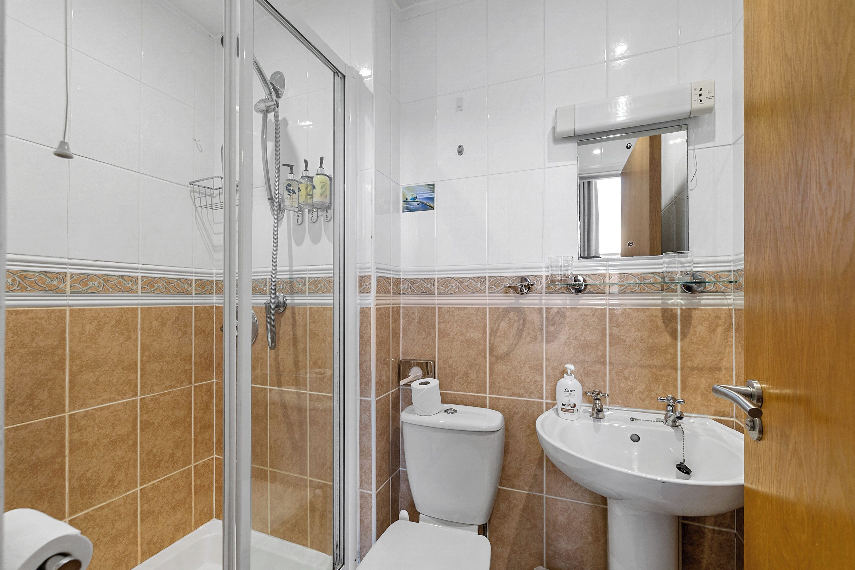 A bathroom with a glass-enclosed shower, a toilet, and a sink.