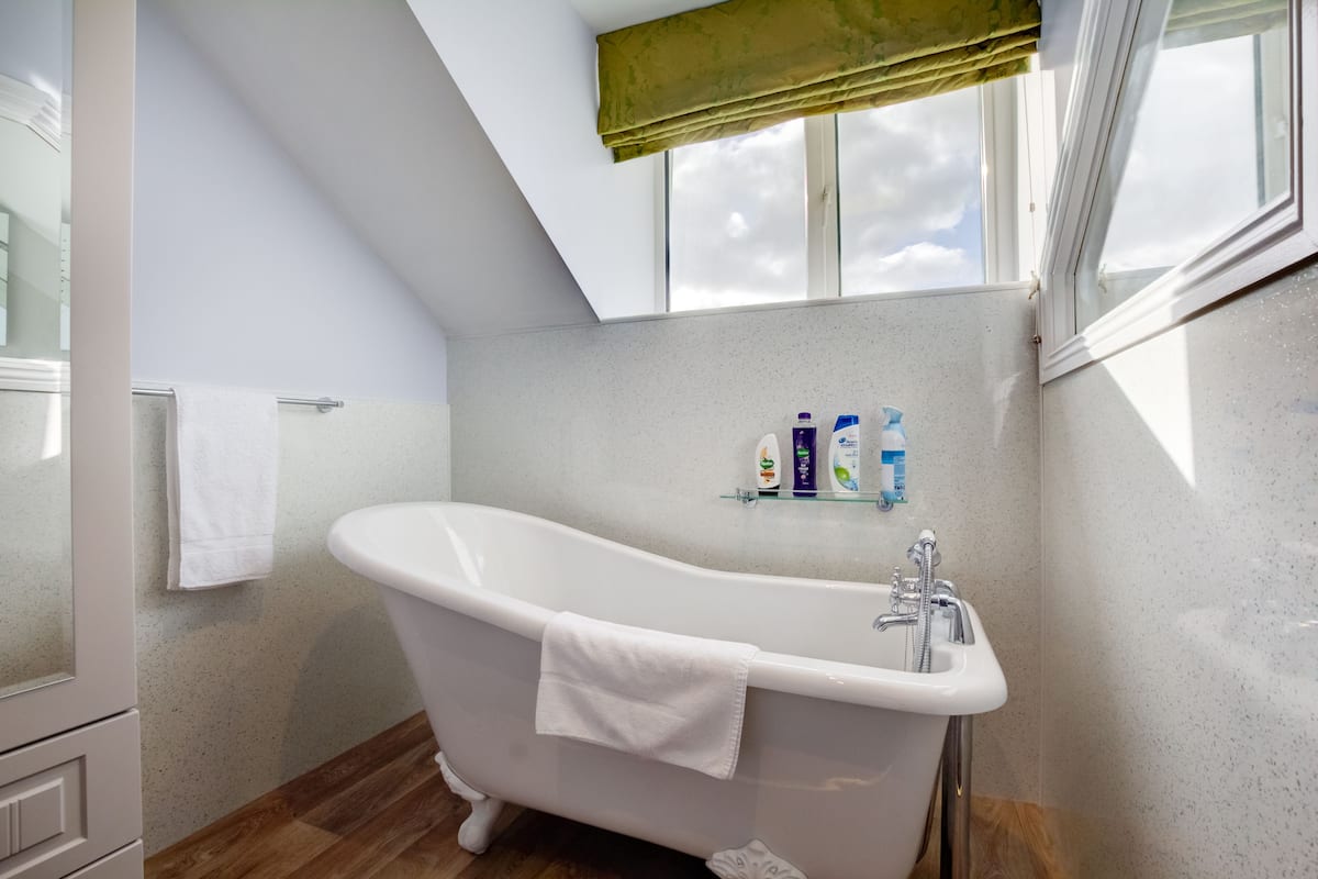 A modern bathroom with a freestanding bathtub, a towel rack, and toiletries on a shelf.