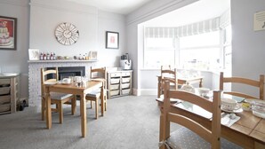 Een lichte keuken met een open haard, houten stoelen en een eettafel gedekt voor vier personen.