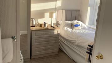 A bedroom with a bed, a dresser, a lamp, and a window.