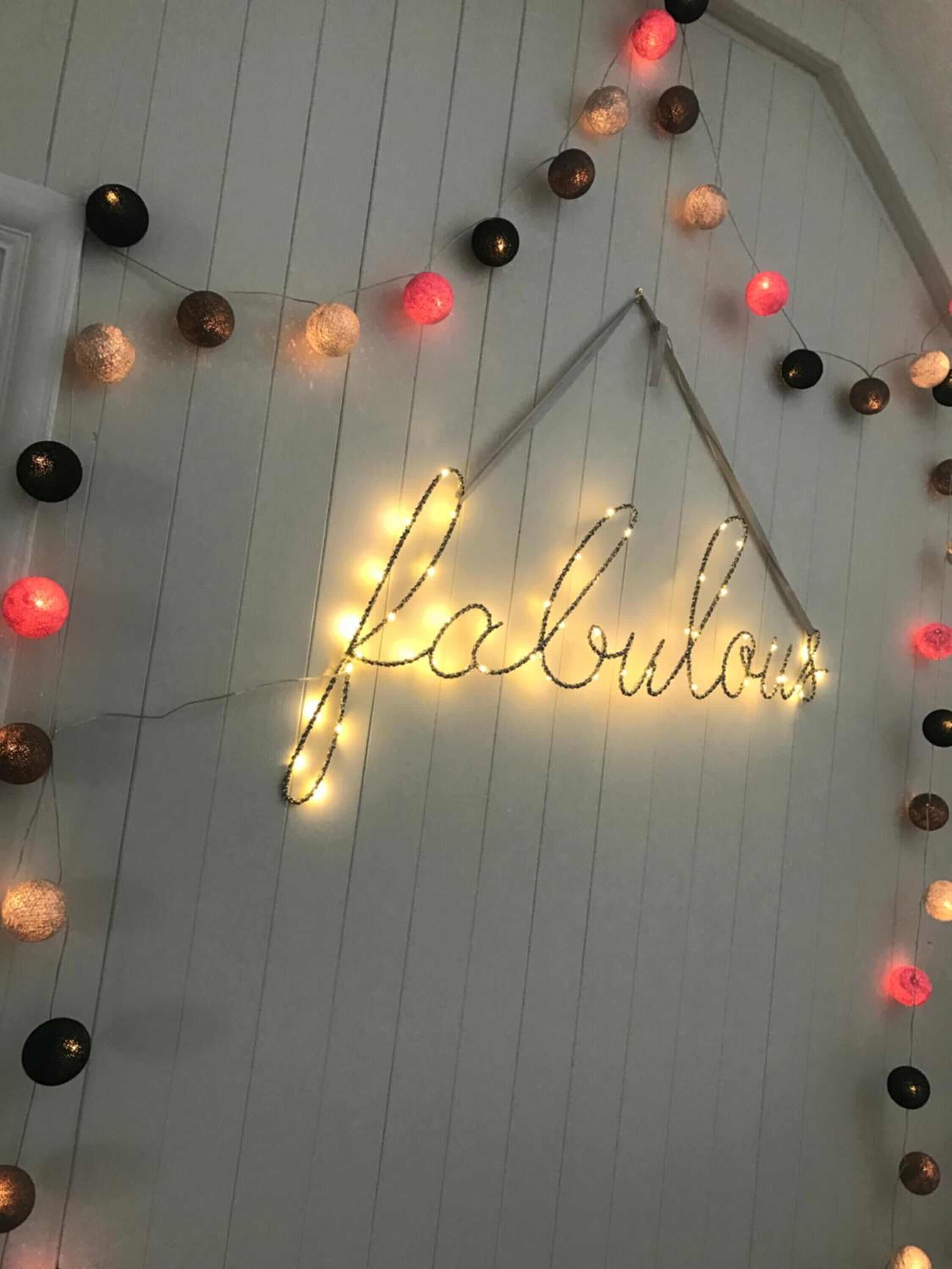A string of lights spelling "fabulous" on a white wall.