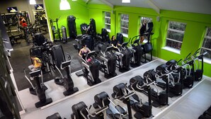 Una palestra con diverse attrezzature per esercizi, tra cui tapis roulant e macchinari per pesi, disposti in file.