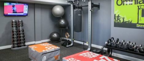 Un gimnasio con equipo de ejercicio, un televisor y un cartel que anuncia Omni Health Club & Spa.