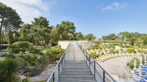 A wooden bridge leading to a pool area with lounge chairs and umbrellas. - Club Vacances Bleues Les Jardins Atlantique (Talmont-Saint-Hilaire)