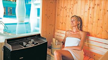 Una sauna con interior de madera, un banco y un calentador.