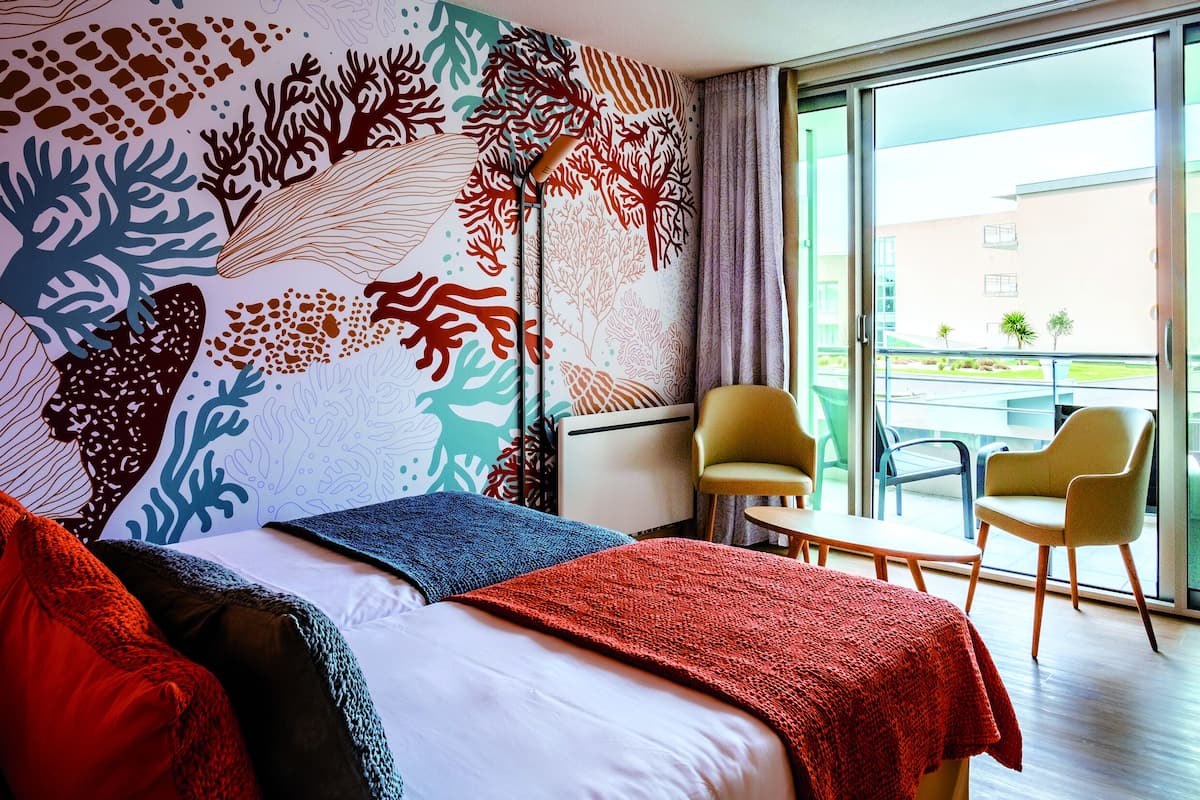 Ein Hotelzimmer mit einem Bett, einem großen Fenster und Blick nach draußen.
