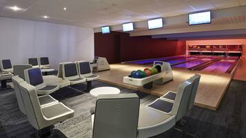 A bowling alley with seating and multiple screens.