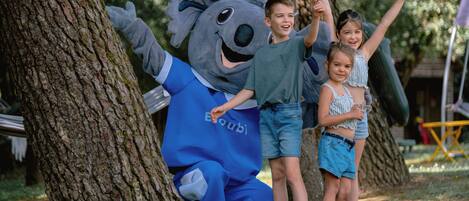 A mascot character interacting with children in an outdoor setting.
