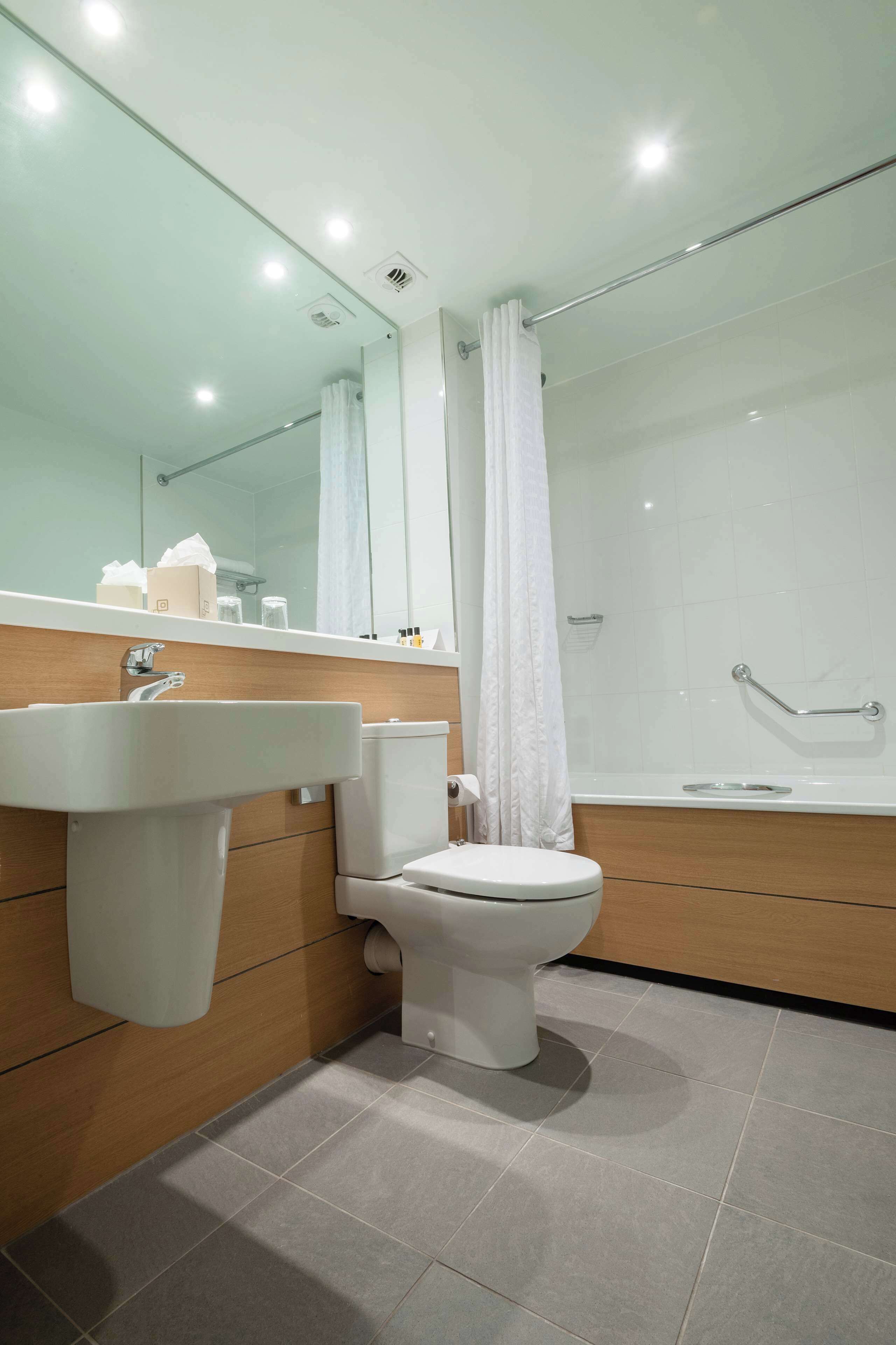 Un baño moderno con lavamanos, inodoro y zona de ducha.