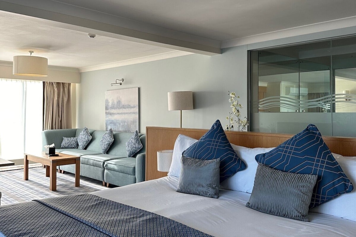Ein Hotelzimmer mit einem großen Bett, einer Couch, einem Couchtisch und einem Fenster mit Vorhängen.