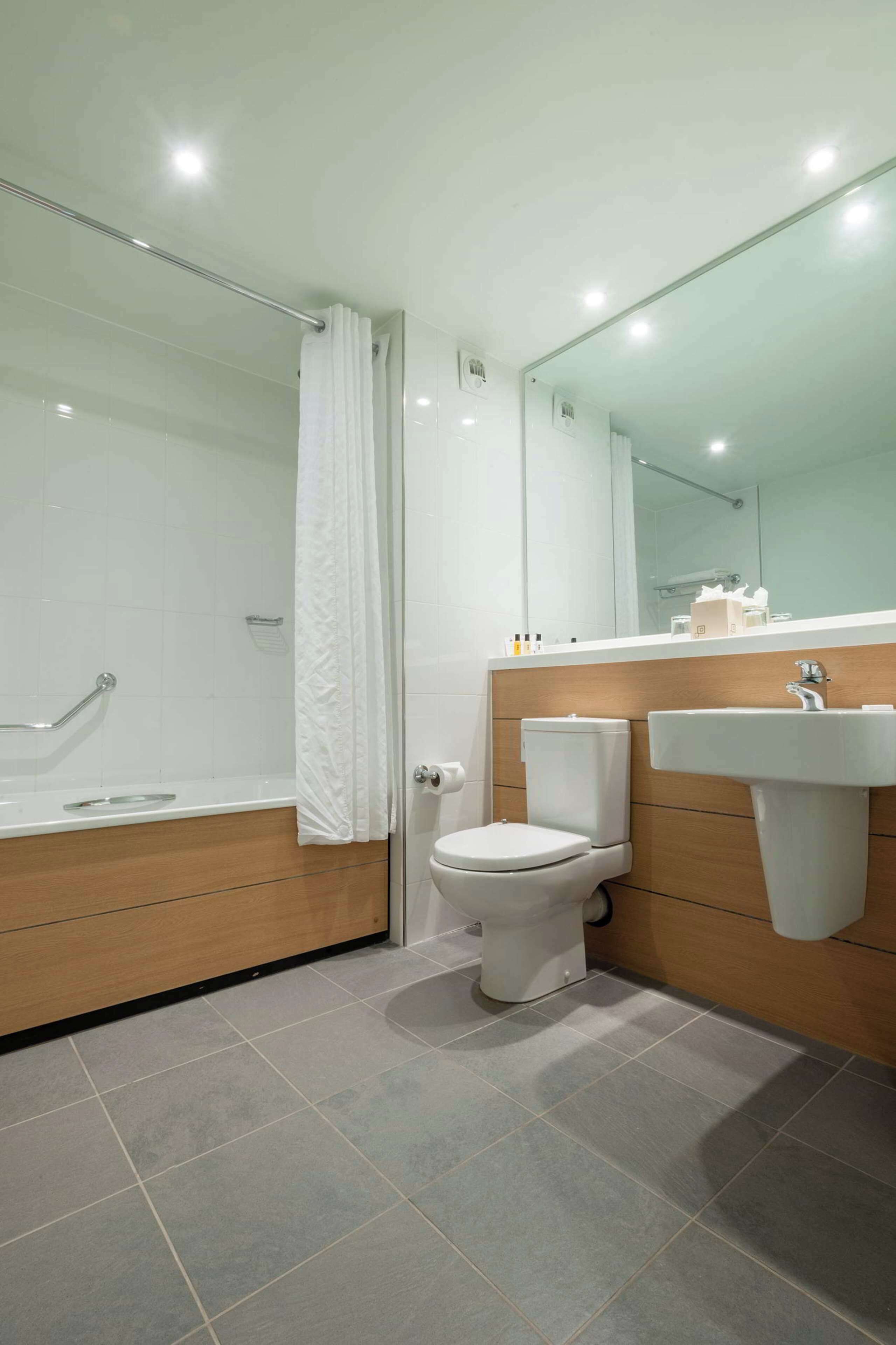 A modern bathroom with a shower, toilet, and sink.