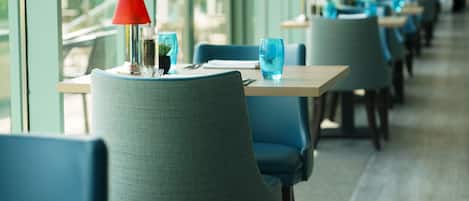 Varias mesas con sillas azules y lámparas de mesa rojas en un restaurante.