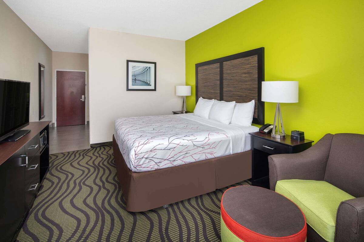 A hotel room with a large bed, a desk, a television, and a chair.