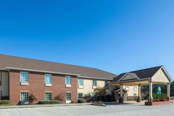 A two-story hotel with a brick facade, a covered entrance, and a parking lot.