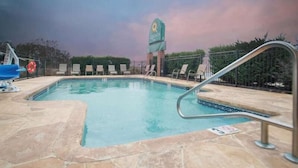 Une piscine avec des chaises longues, une bouée de sauvetage et un panneau indiquant « QUINTA ».