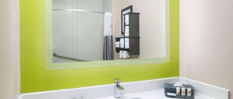 Un baño de hotel con un espejo grande, un lavamanos y un perchero para toallas.