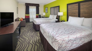 Une chambre d’hôtel avec un lit, un bureau avec une télévision, une chaise et une fenêtre avec des rideaux.