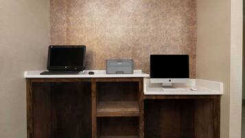 A workspace with a laptop, desktop computer, and printer on a white desk against a textured wall.