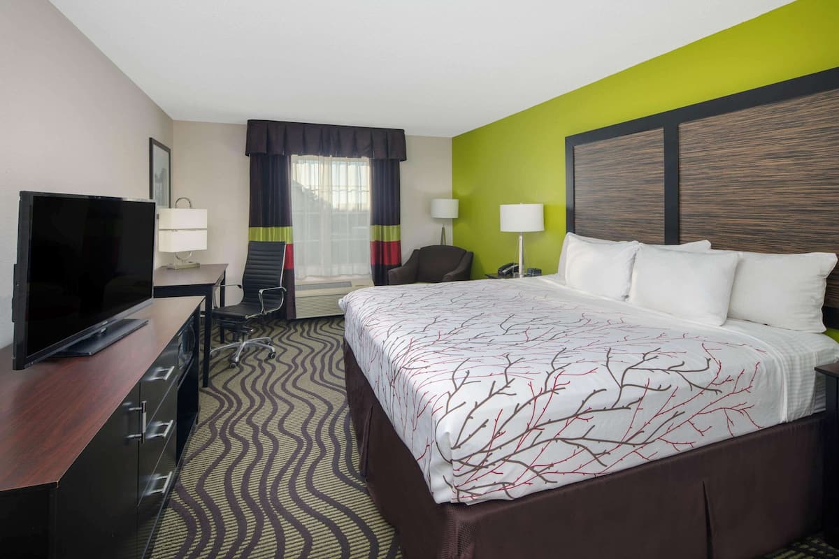 A hotel room with a bed, a TV, a desk, and a chair.