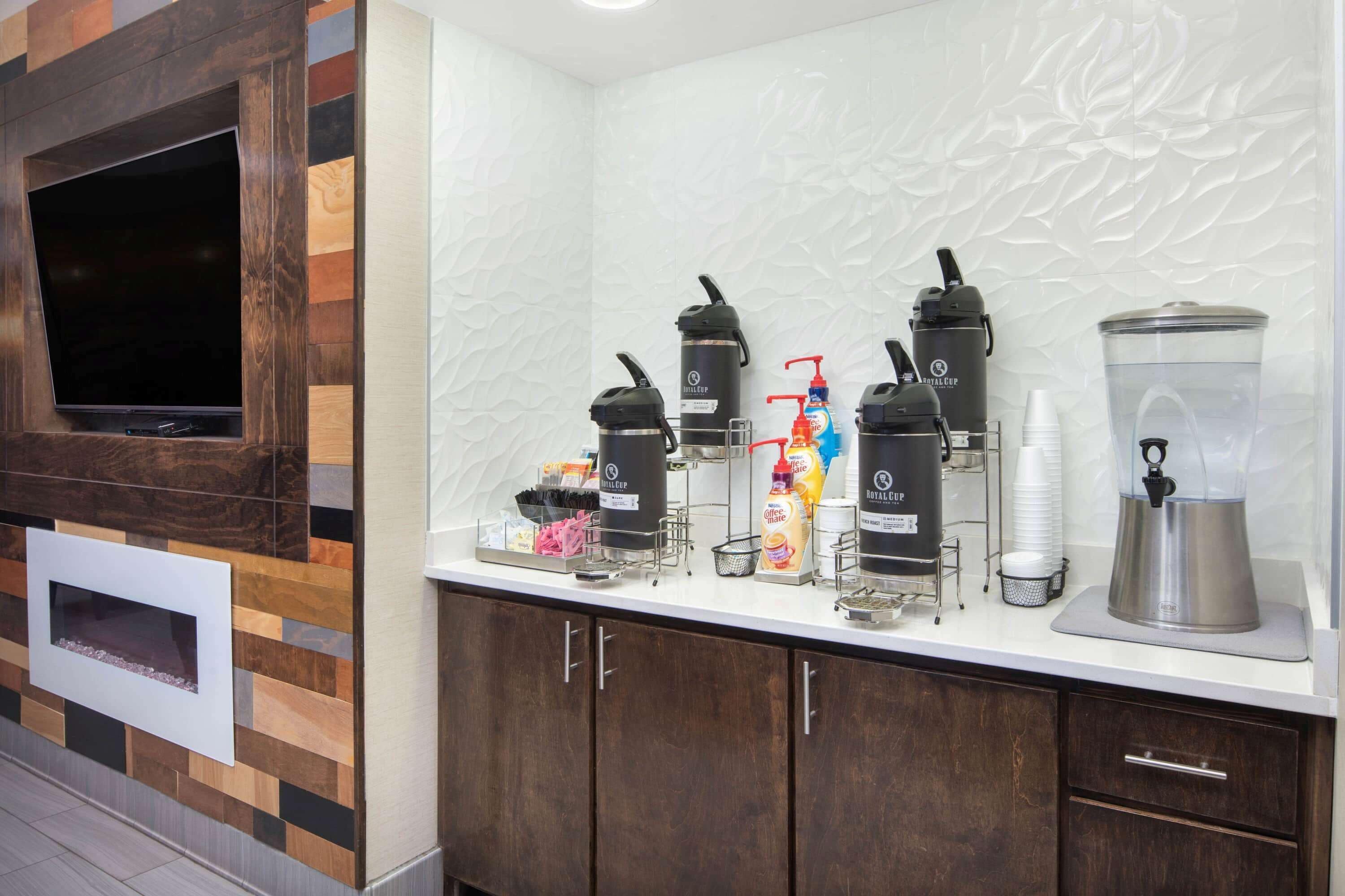 A kitchen area with a built-in TV, coffee makers, and a blender on the counter.