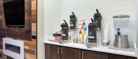 A kitchen area with a built-in TV, coffee makers, and a blender on the counter.