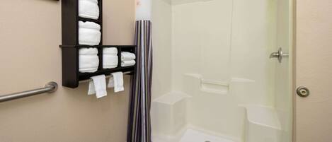 A shower with a glass door, a towel rack with folded towels, and a striped shower curtain.