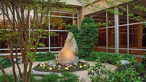 A landscaped garden with a large rock centerpiece, surrounded by various plants and flowers.