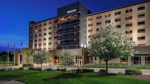 A Westin hotel with a modern facade, multiple floors, and a well-maintained garden area.