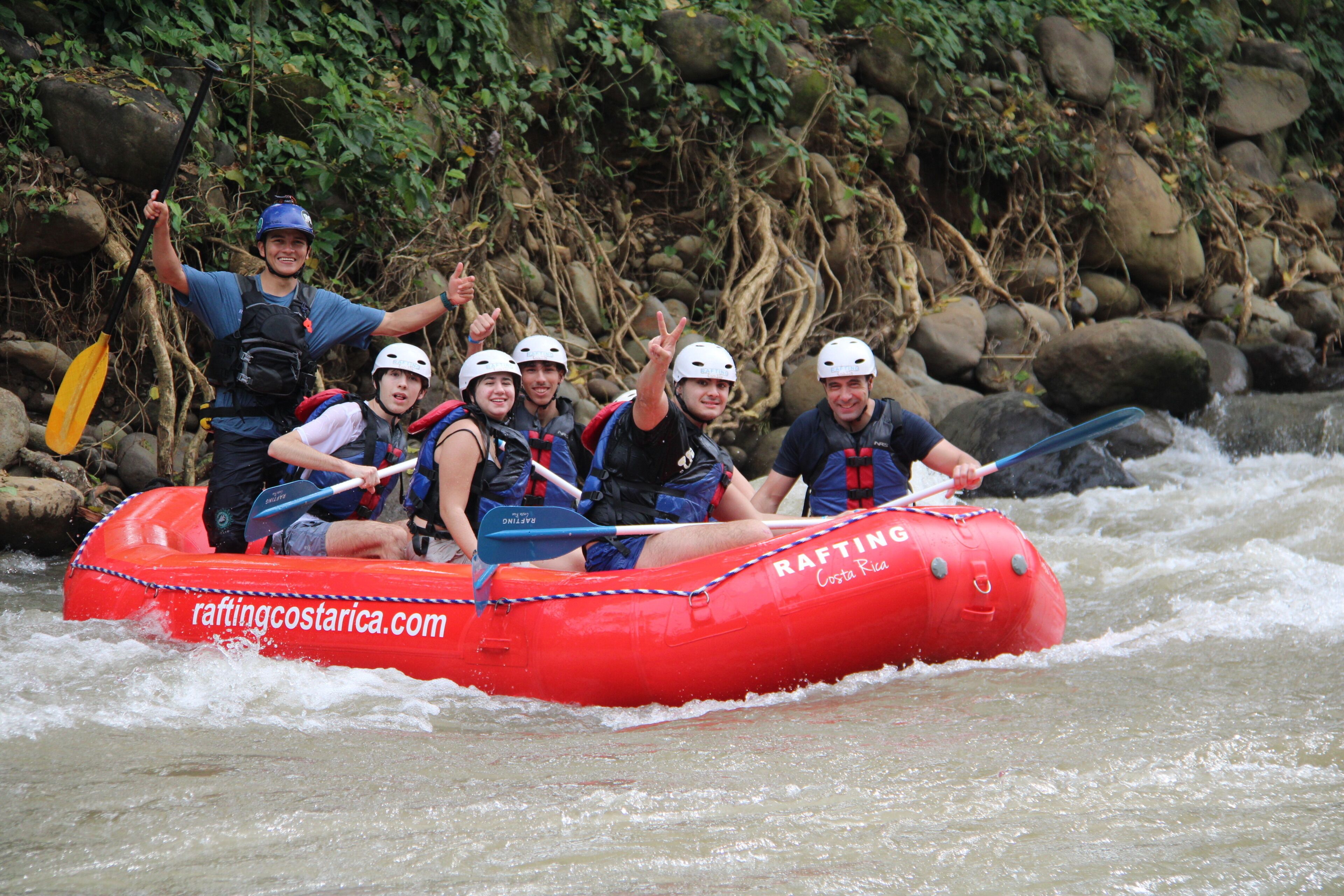 A group of people in a red inflatable raft on a river.