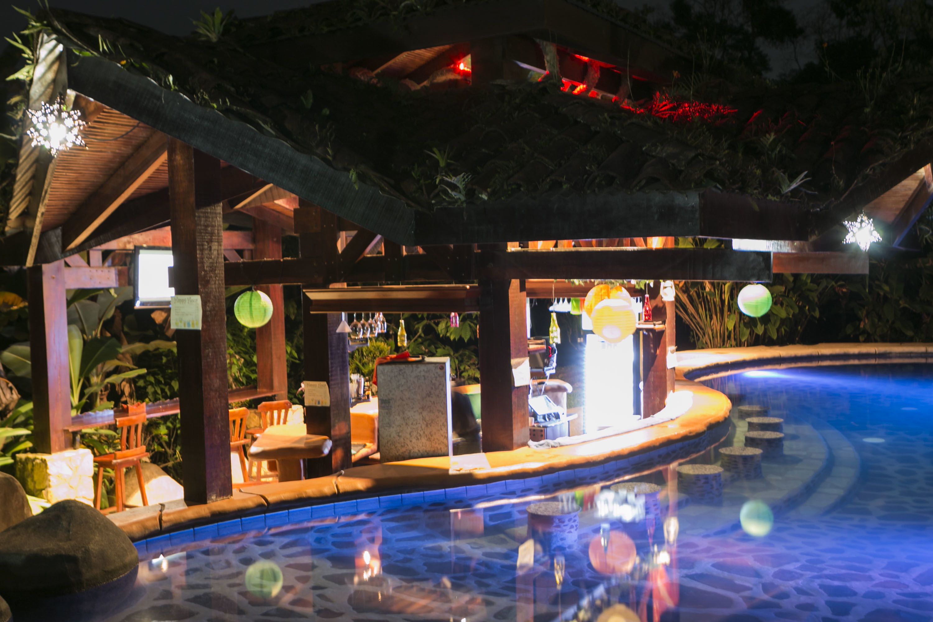 A poolside area with a covered seating area, lounge chairs, and a bar.